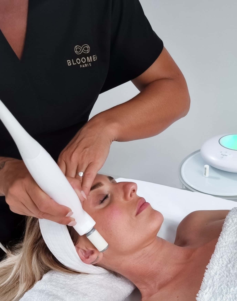 A Bloomea practitioner using the La Fontaine handpiece on a client’s cheek